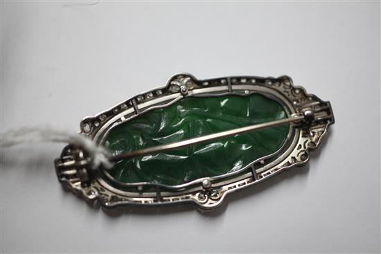 A 1920s/1930s Art Deco white gold?, pierced carved jadeite, diamond and black onyx set oval brooch, 53mm.